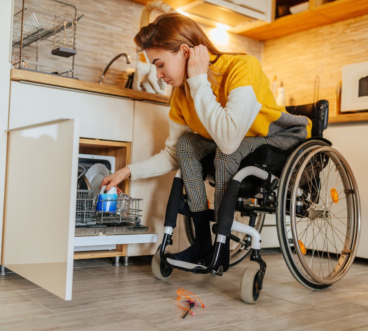 Woman in wheelchair puts dishes in dishwasher